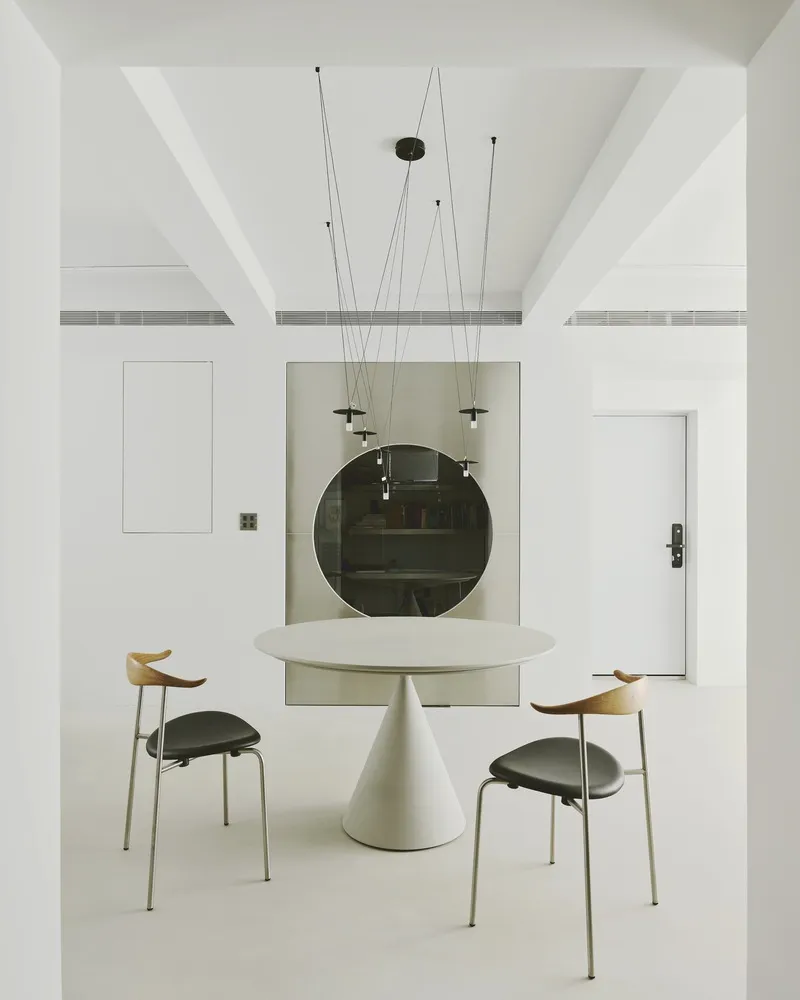 Dining area with coffered ceiling beams and circular dark mirror set in grey panel niche