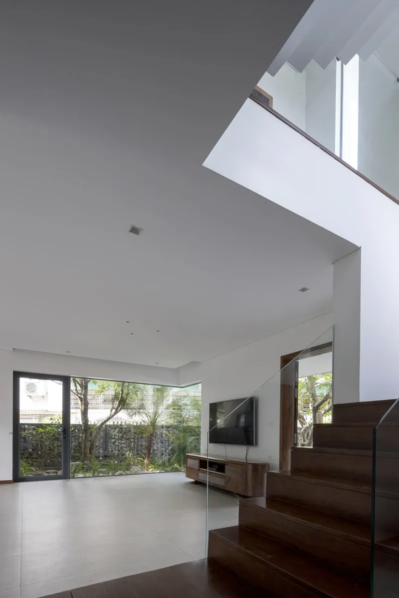 Double-height living space with dark timber staircase rising past a skylight opening above