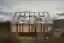 This architectural image showcases a modern greenhouse nestled within a natural landscape. The struc