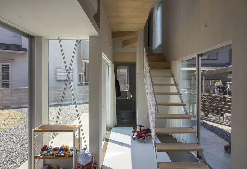 Open timber staircase with steel cable railings ascending through a double-height space with glazed walls