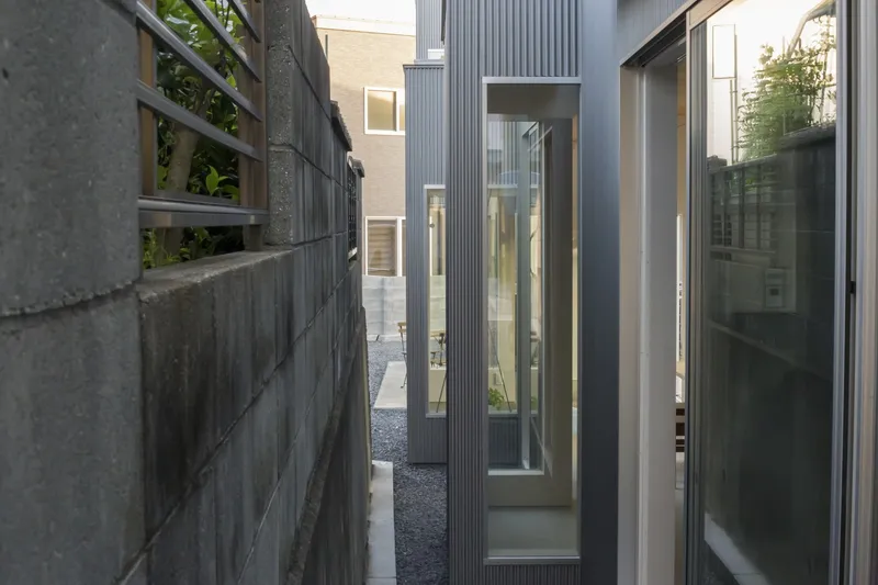 Narrow courtyard between corrugated metal facades and a concrete block wall at dusk