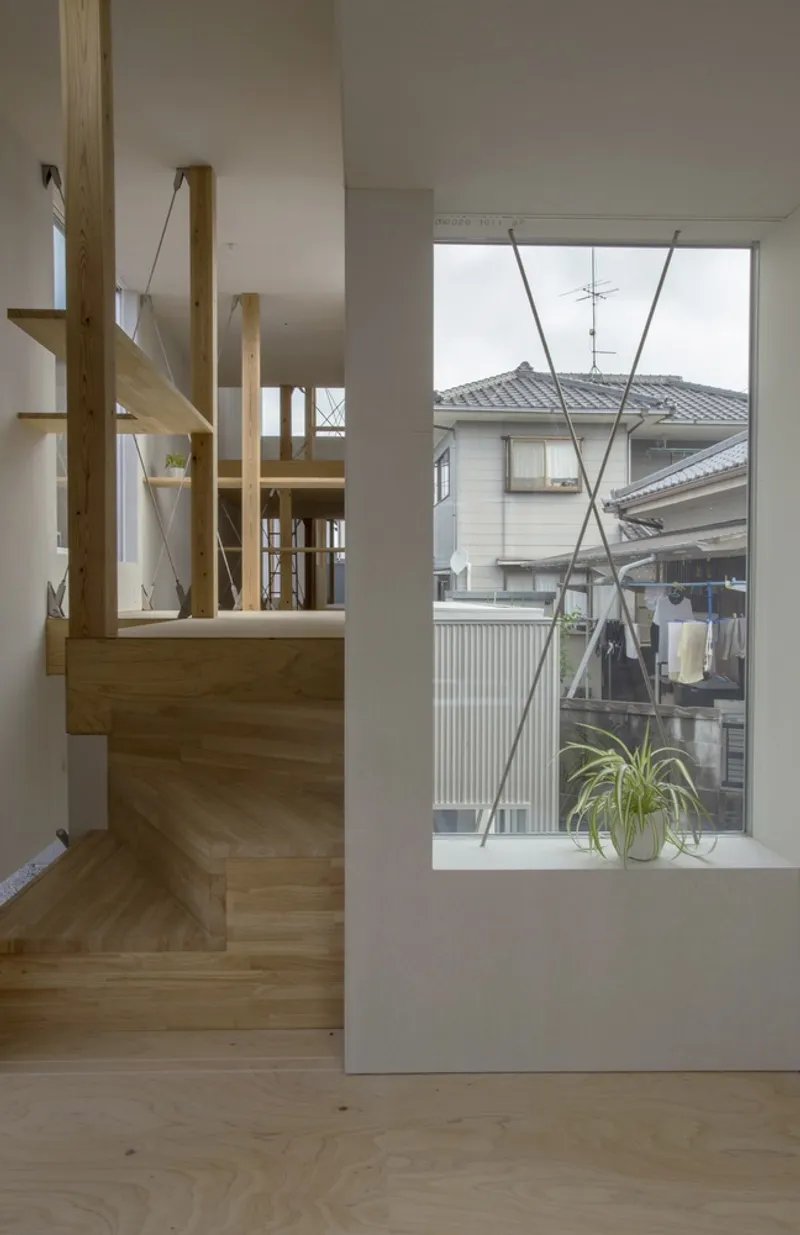 Interior view of timber staircase with wire railings and window overlooking neighboring rooftops