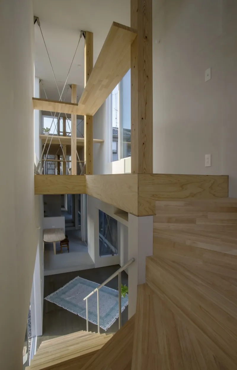 Timber staircase with exposed posts and beams descending through split-level floors in afternoon light