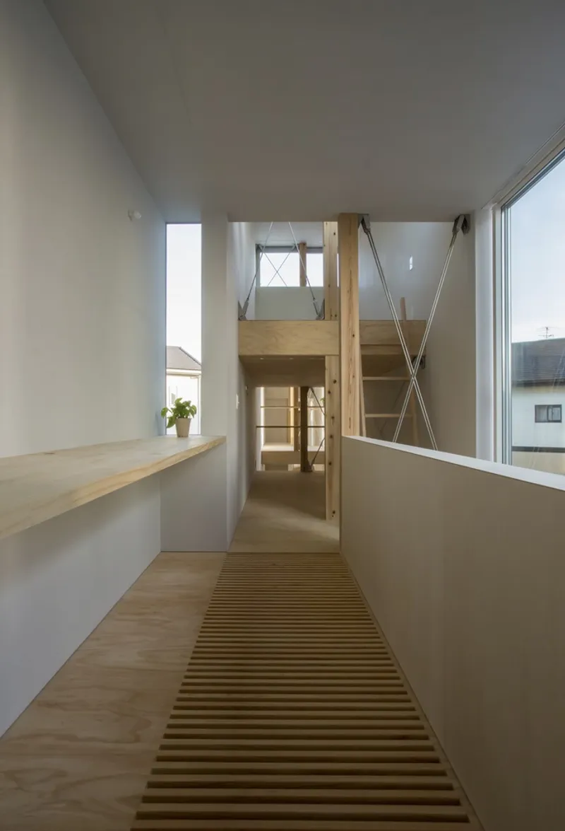 Upper-level corridor with slatted timber floor panels and steel cable handrail overlooking a stairwell below