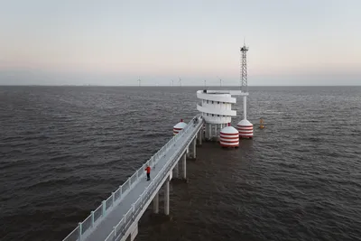 This architectural image showcases a modern pier extending into the sea, featuring a white, cylindri