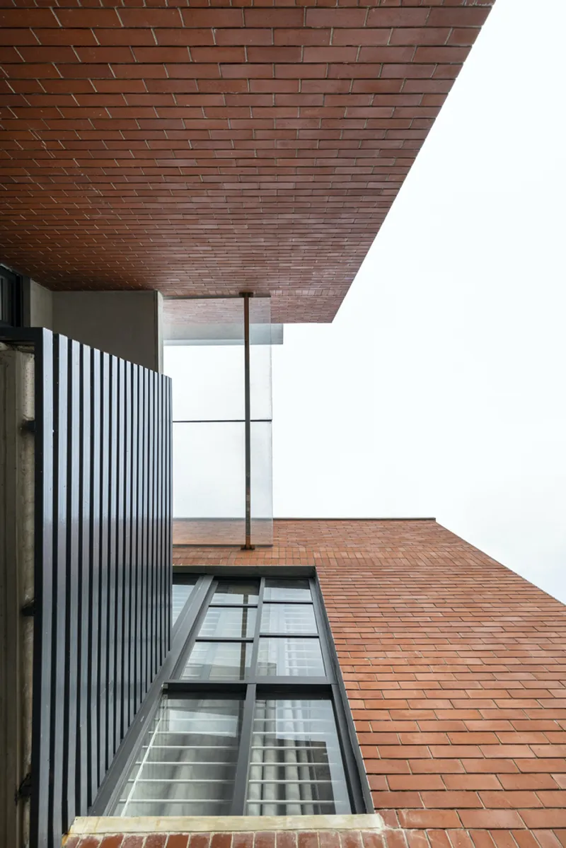 Overhead view of brick-clad soffit extending over glass skylight and metal louvered wall