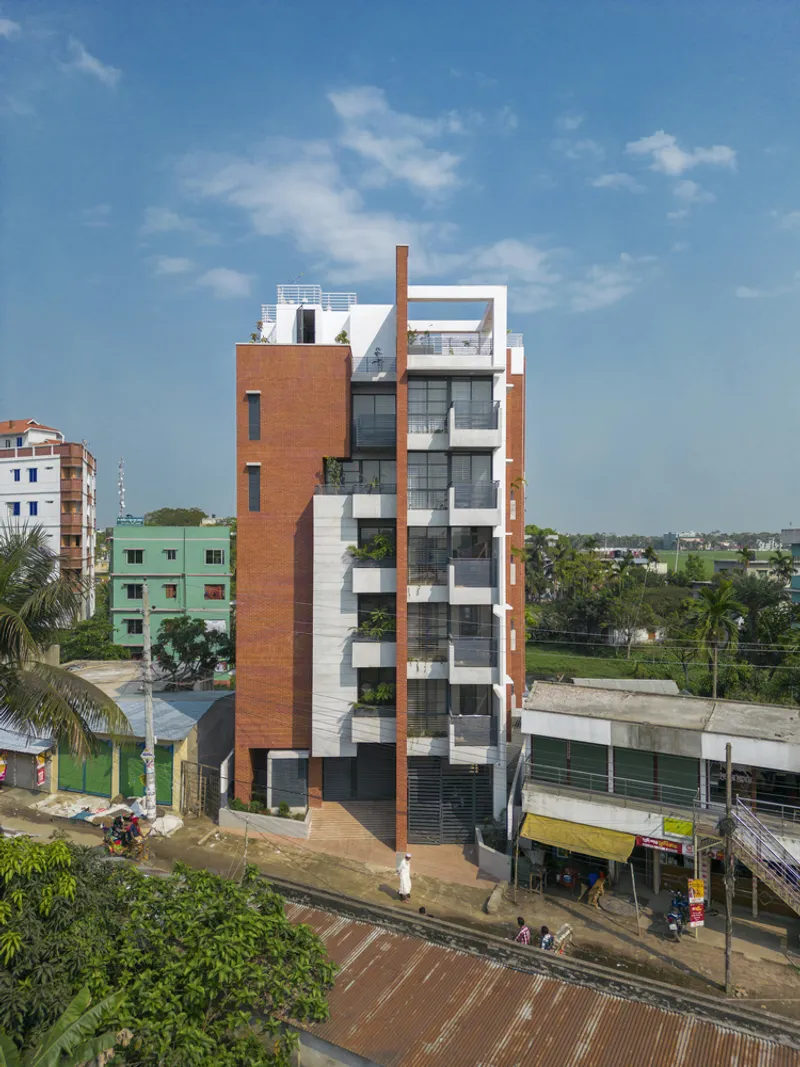 Elevated view of the residential tower set among palm trees and neighboring low-rise buildings