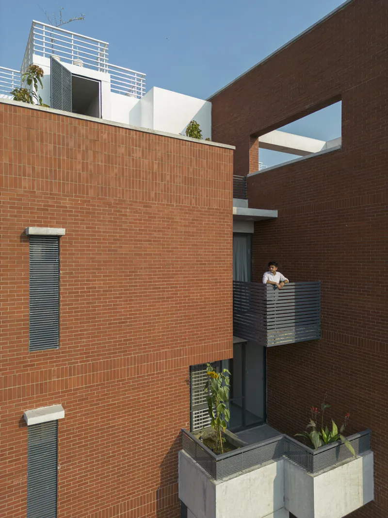 Interior courtyard framed by brick walls with balconies and a resident visible on upper level