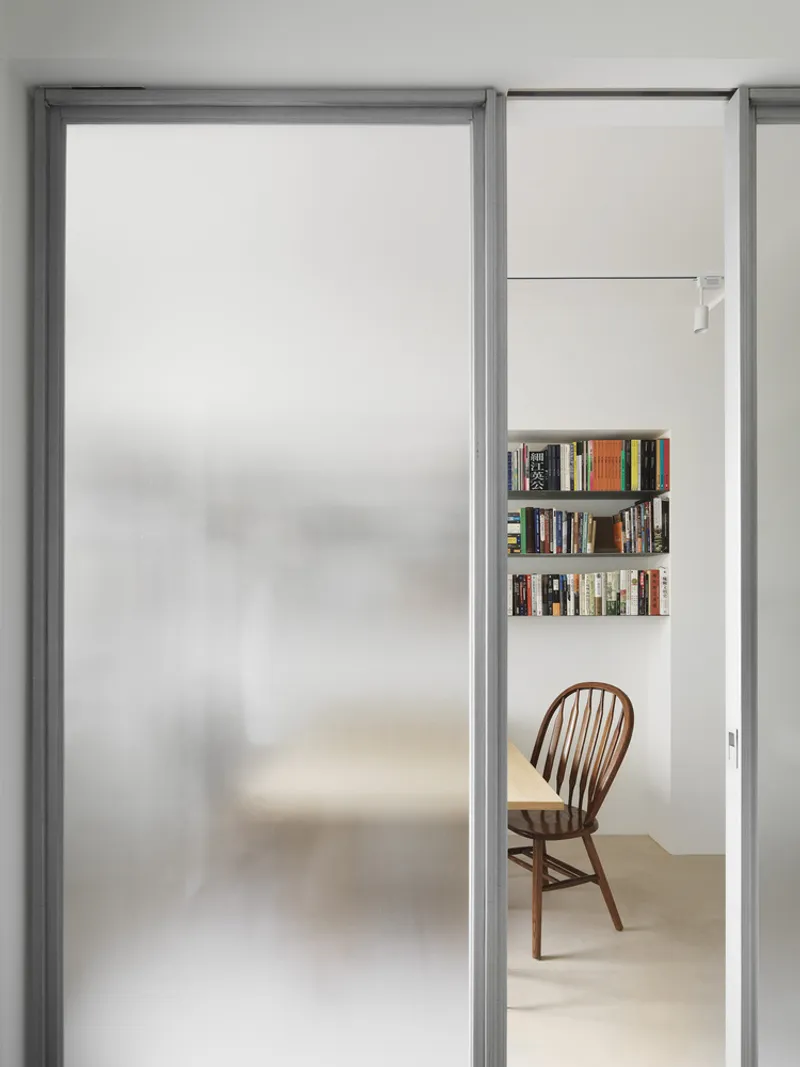 Frosted glass sliding door partially open to reveal bookshelves and a wooden chair beyond