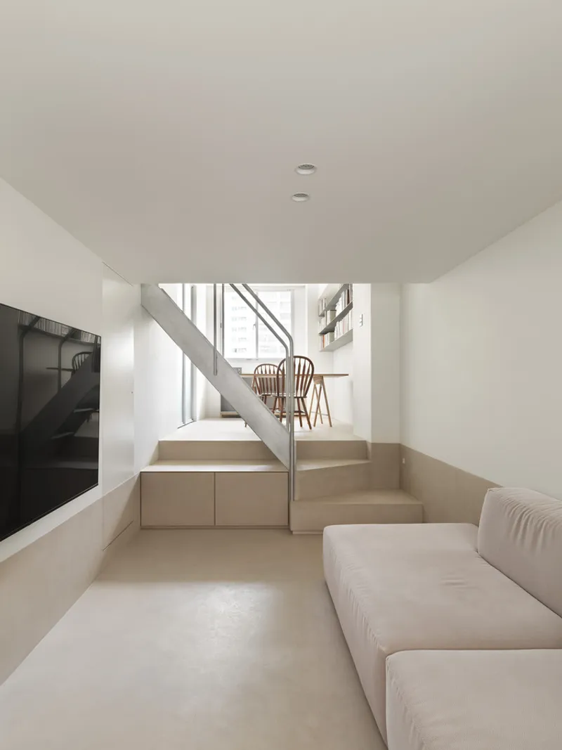 Sunken living room with integrated timber steps and steel handrail ascending to dining level