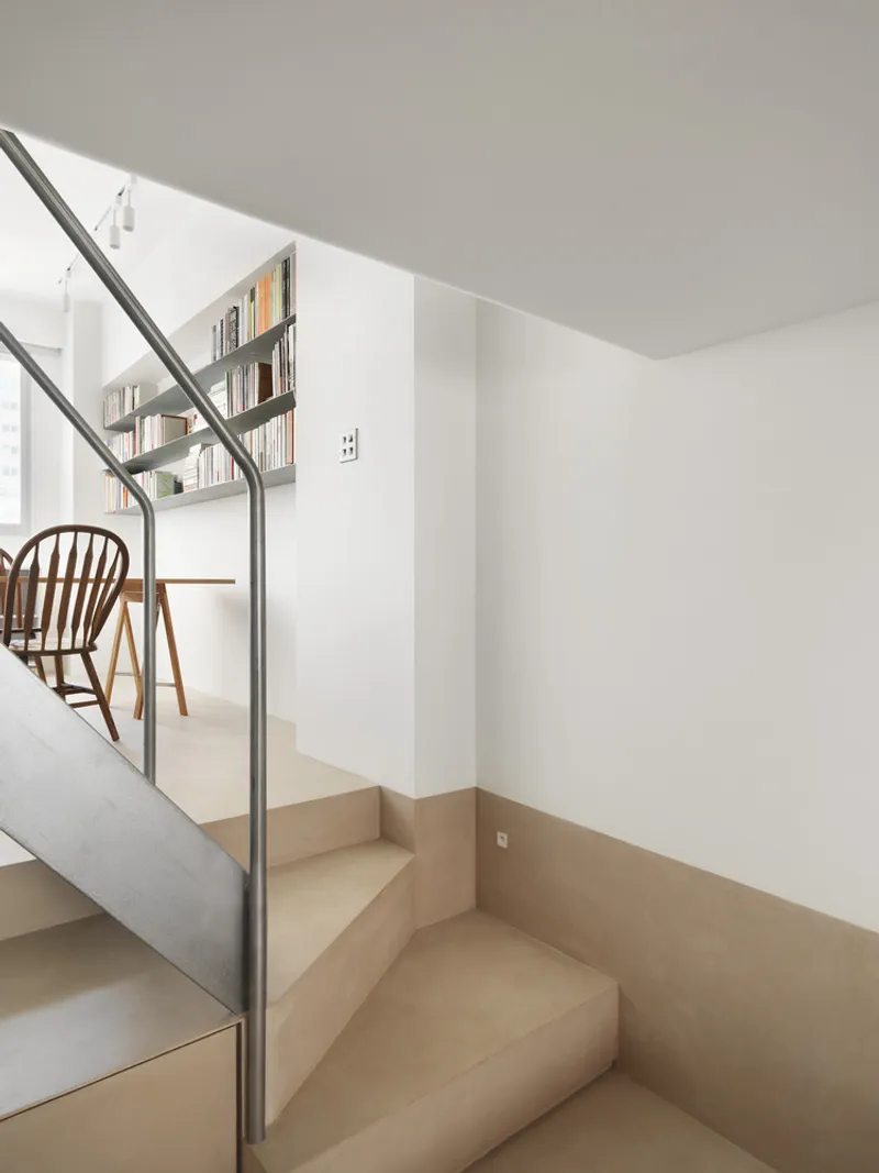 Lower treads of timber staircase with steel handrail in bright natural light