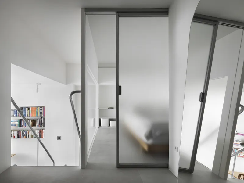 Frosted glass sliding door with dark metal frame and blurred figure passing through