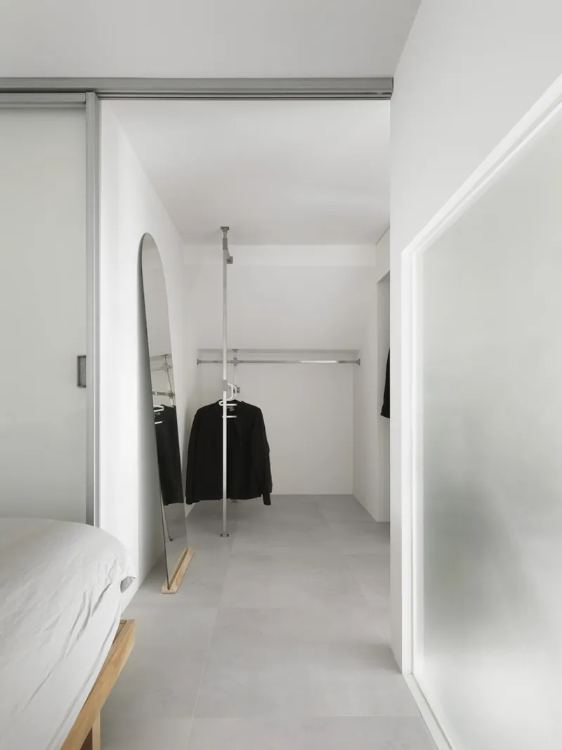 View into closet space with exposed hanging rod and arched mirror reflecting the interior
