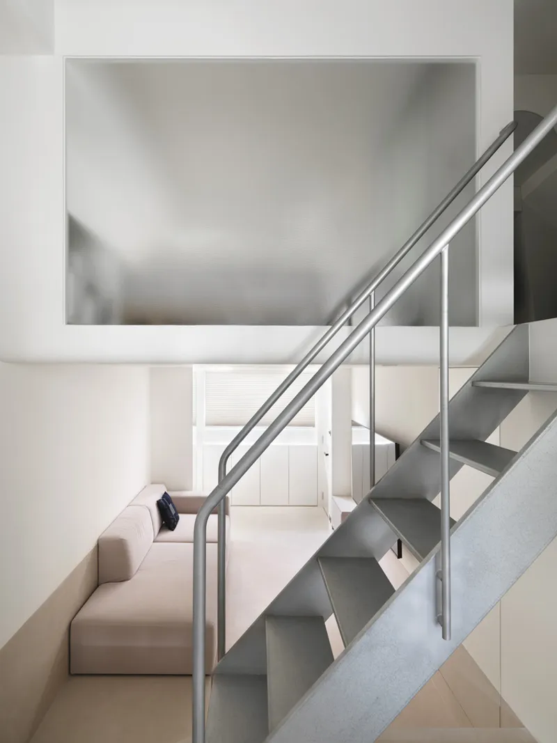 View up steel staircase showing rectangular skylight above and recessed entry door below