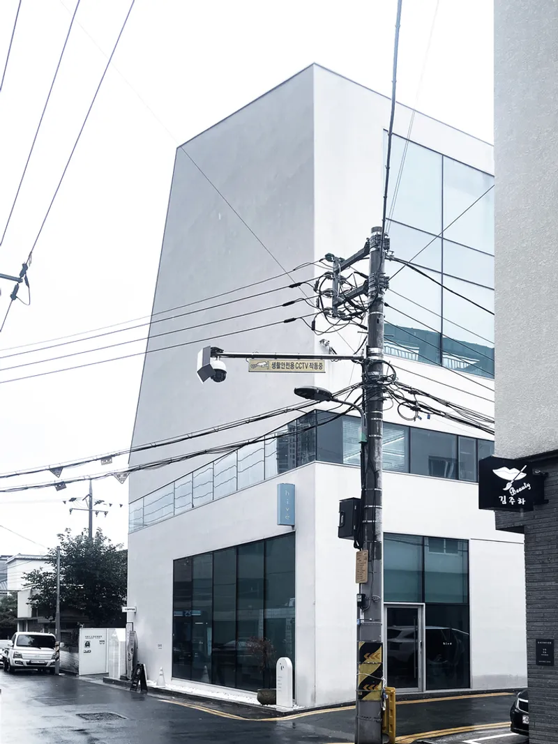 Street corner view of the white facade with glass storefronts and overhead power lines