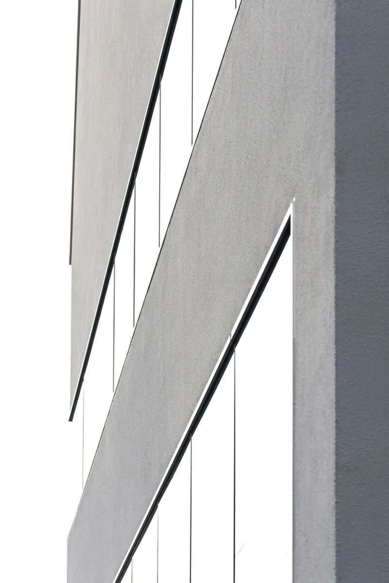 Abstract detail of diagonal shadow lines cutting across the white rendered facade in bright daylight