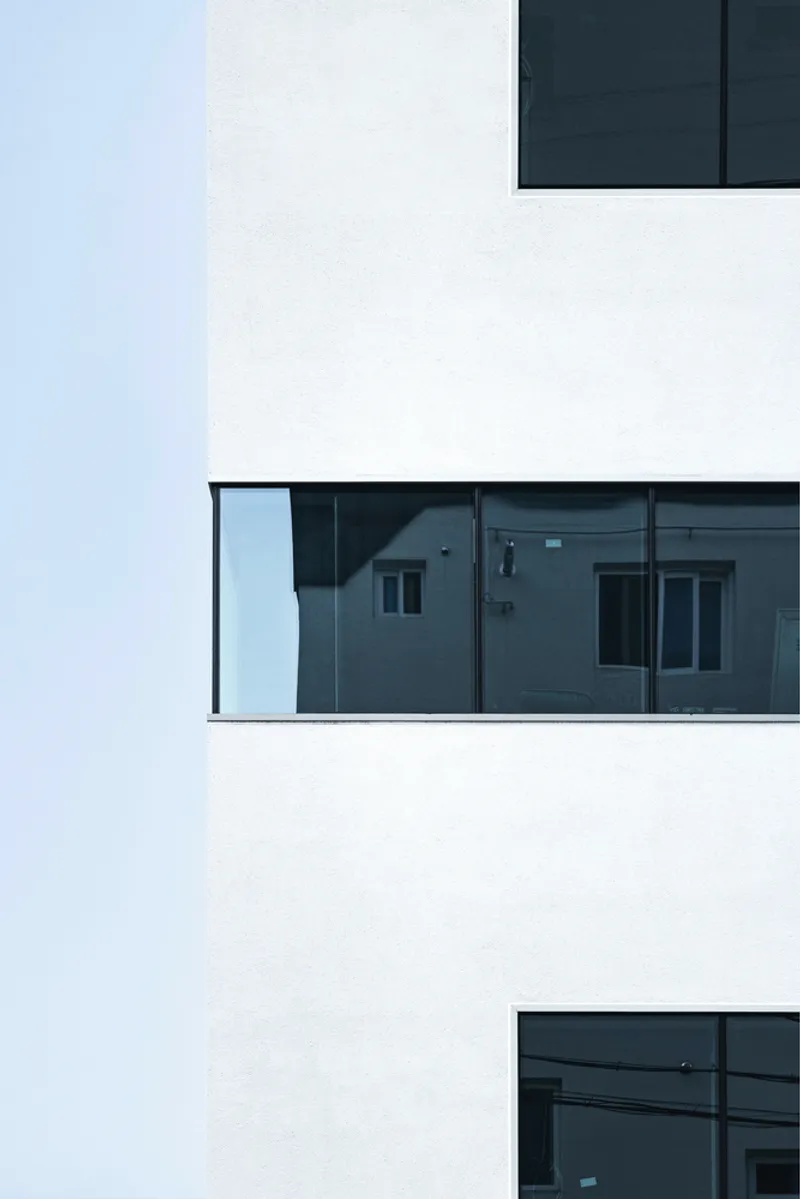 Stacked white volumes with recessed glazed balconies reflecting adjacent residential buildings