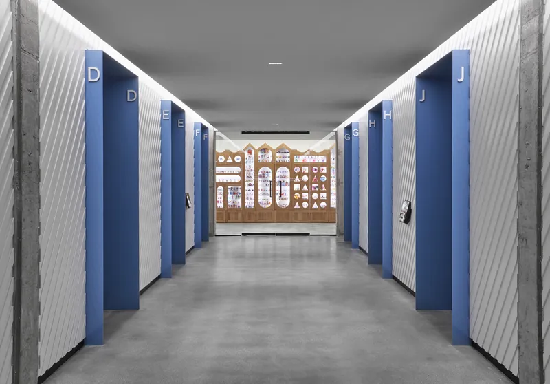 Corridor with alternating blue and white ribbed wall panels leading to decorative end wall