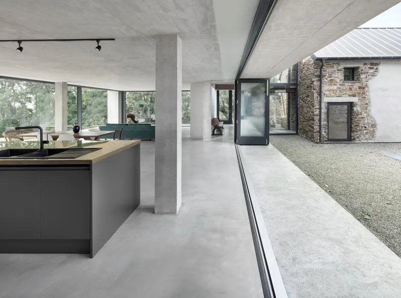 Open plan kitchen and living space with exposed concrete ceiling opening to courtyard