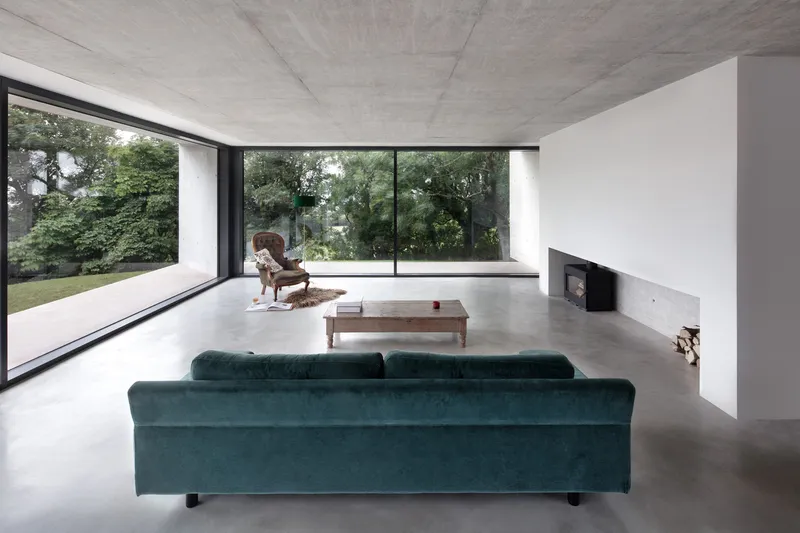 Living room with corner glazing framing garden views and person seated in chair