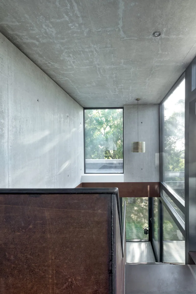 Stairwell with steel handrail and vertical window framed by board-formed concrete walls