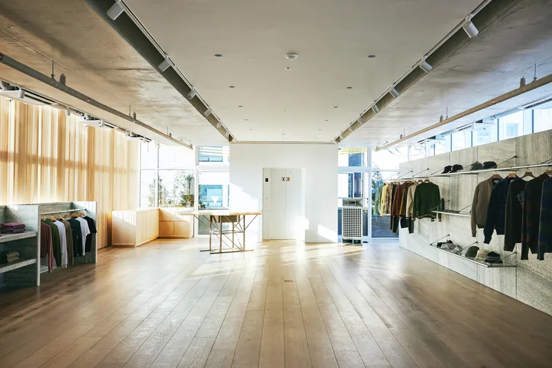 Second floor: wide open plan with hanging rails on both sides, timber slat wall with golden light, plywood display, oak floor