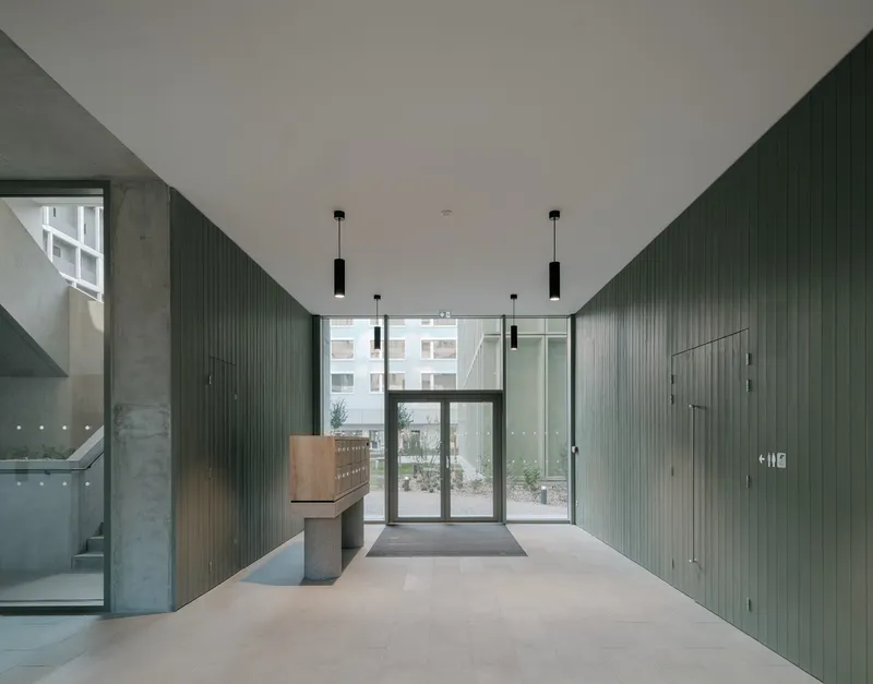 Lobby interior with vertical green wall panels, black pendant lights and polished concrete floor