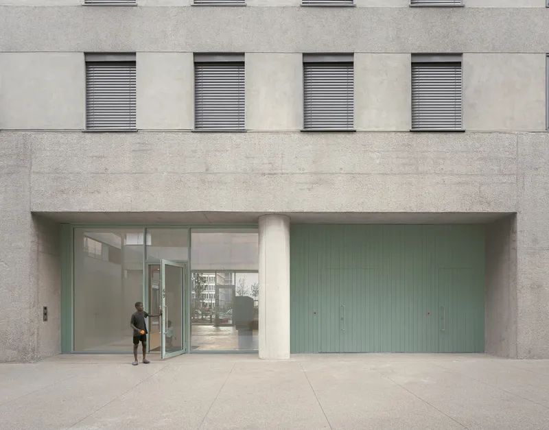 Street-level entrance with pale green vertical paneling and a figure standing near the glass doors