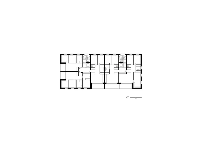 Floor plan drawing depicting residential units with two spiral staircases flanking the central corridor