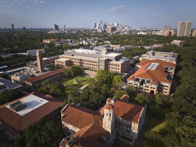 Aerial view of the campus buildings with red clay tile roofs and clock tower surrounded by green lawns and trees