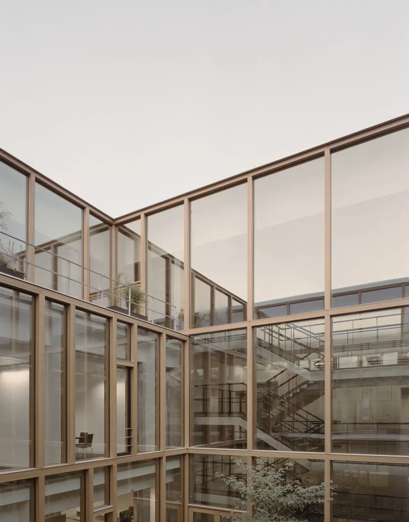Interior courtyard framed by timber-framed glazing with metal staircase visible through the glass