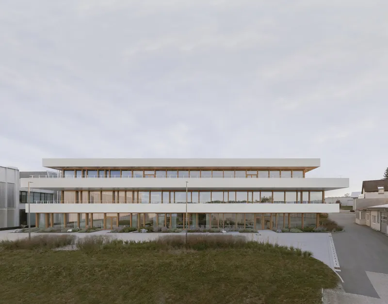 Street view of the three-level horizontal facade with continuous glazing and timber structure in winter