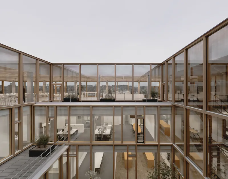 Three-story glazed atrium with timber framing overlooking multiple floors of office space under overcast sky