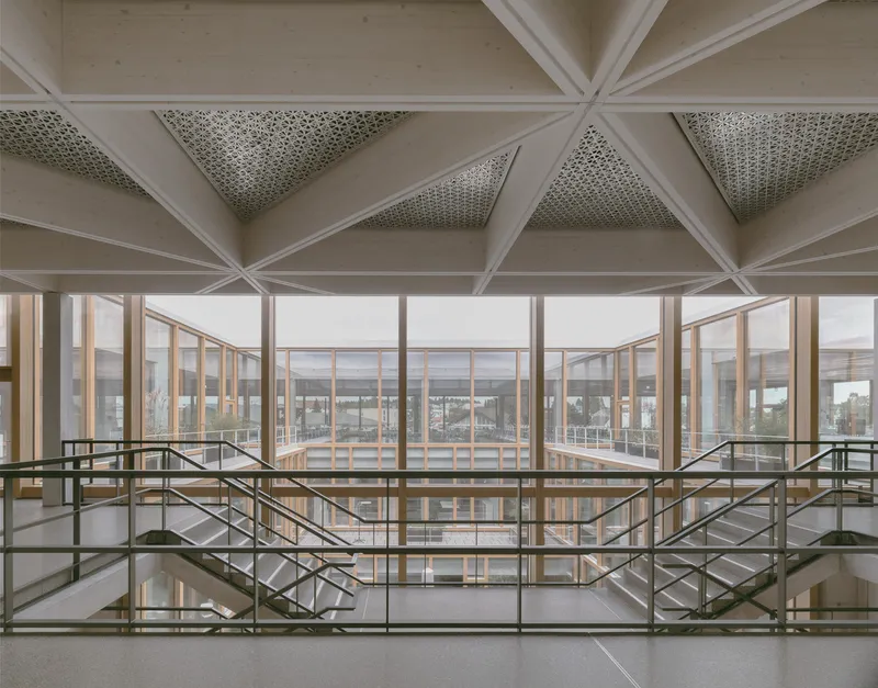 Interior view of geometric coffered ceiling with perforated panels above a steel and glass mezzanine balustrade