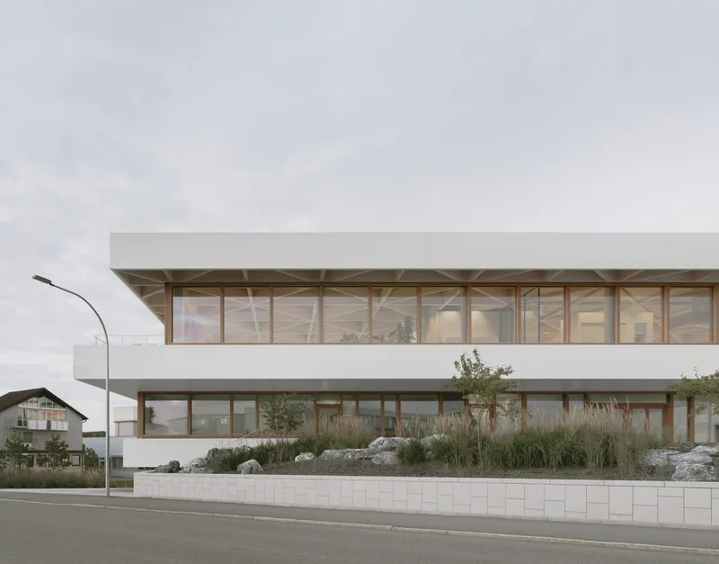 Street view of the two-story timber-framed facade with planted berm and white block retaining wall