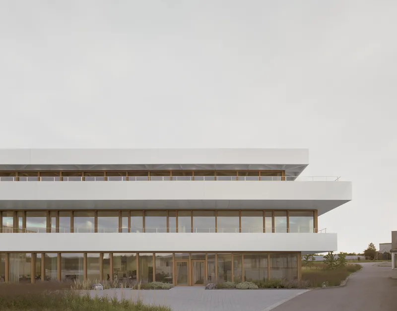 Stacked timber-framed terraces with glass walls overlooking native grasses at dusk