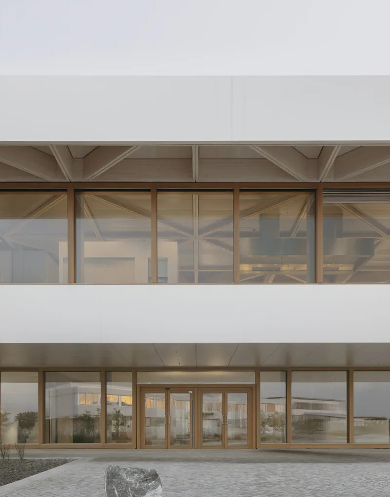 Close-up of timber-framed glazing with exposed ceiling beams reflected in the glass
