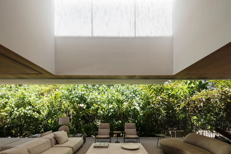 Covered terrace with horizontal window slot framing dense tropical foliage behind seating area