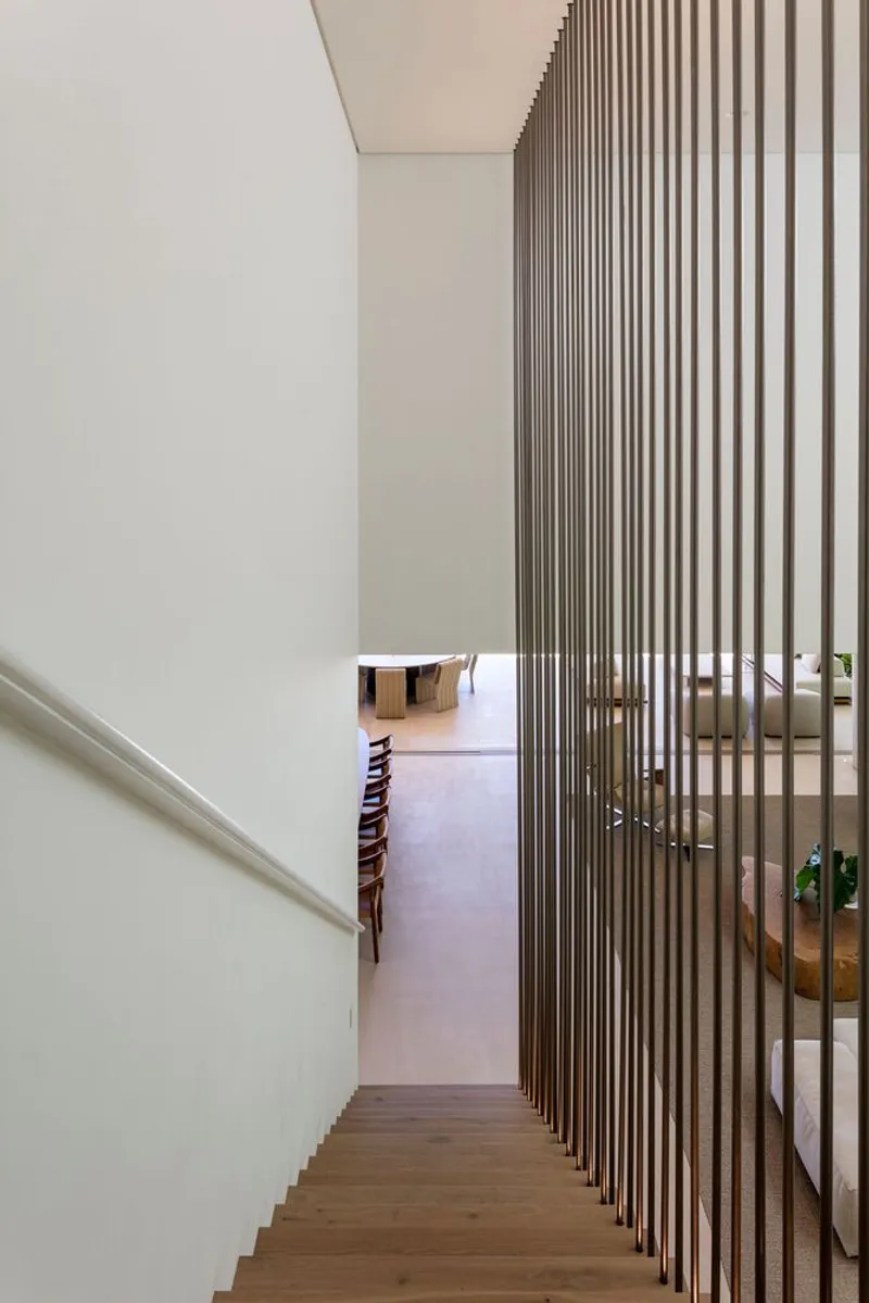 Timber staircase descending past a vertical slat screen filtering light into the upper level hallway