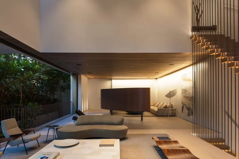 Living area with vertical timber slat screen alongside staircase and full-height glazing opening to garden