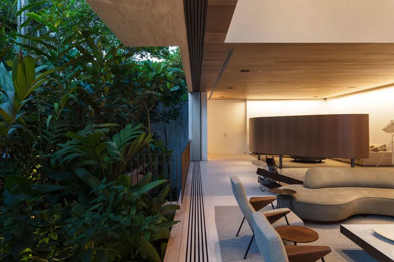 Living room edge opening to planted courtyard with tropical foliage at twilight