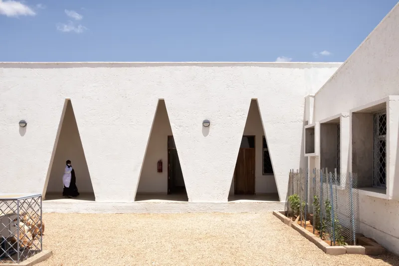 Courtyard wall: three triangular windows, figure passing, low planting along the base