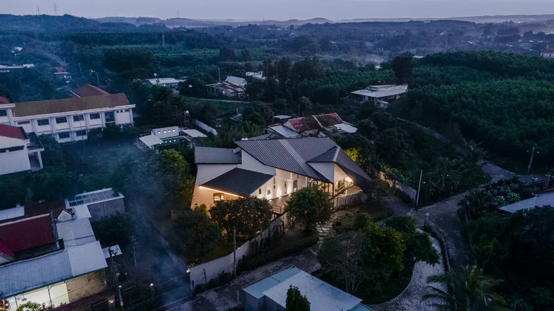 Aerial view of the gabled metal roof structure illuminated at dusk among surrounding residential buildings