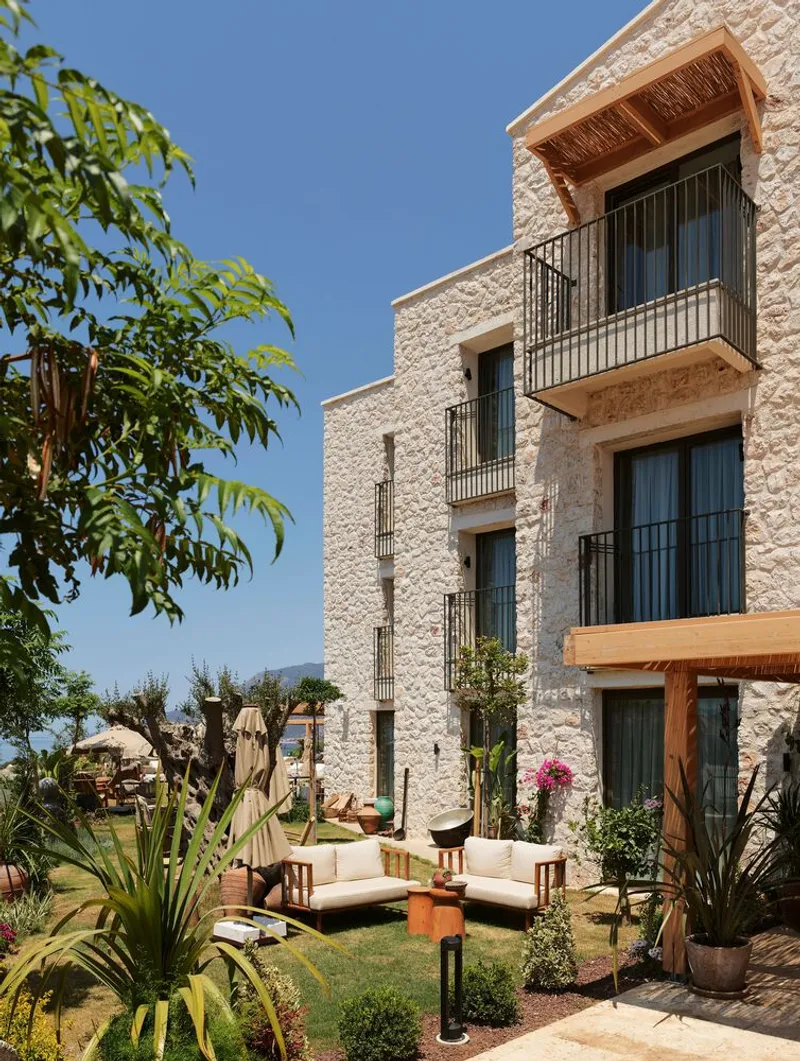 Facade of textured stone cladding with recessed balconies and timber pergola framing a planted courtyard