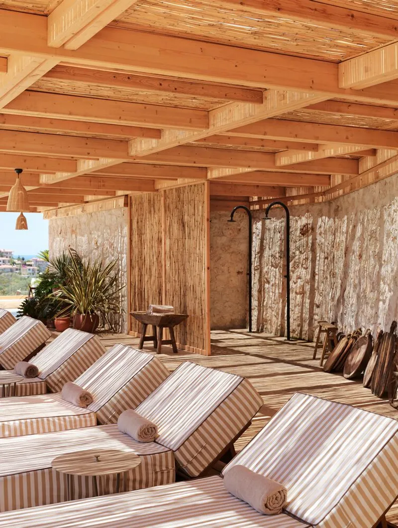Rooftop lounge area with exposed timber beam ceiling and weathered stone privacy screens