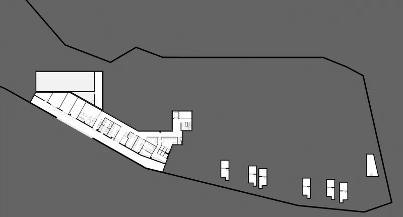 Site plan drawing showing sloped terrain with linear building and scattered smaller volumes below