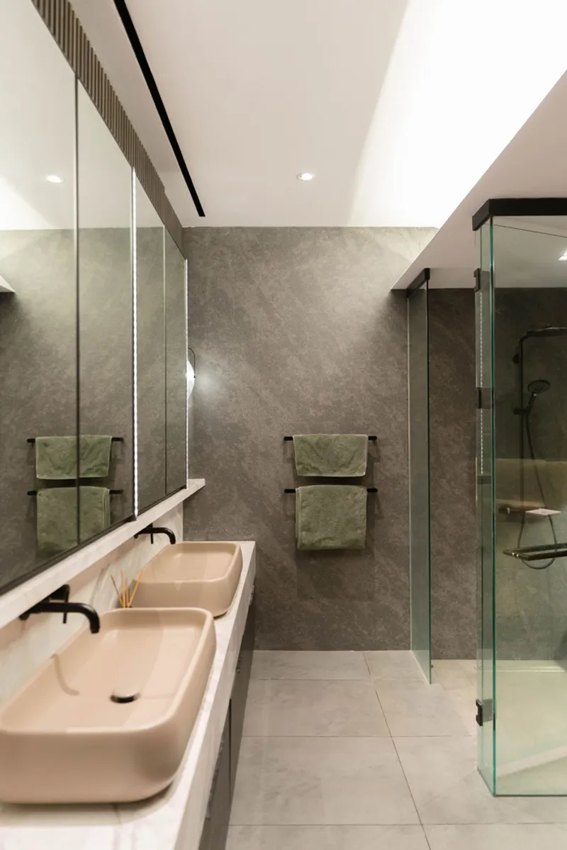 Bathroom interior showing dual vessel sinks, towel rails and glass-enclosed shower with skylight above