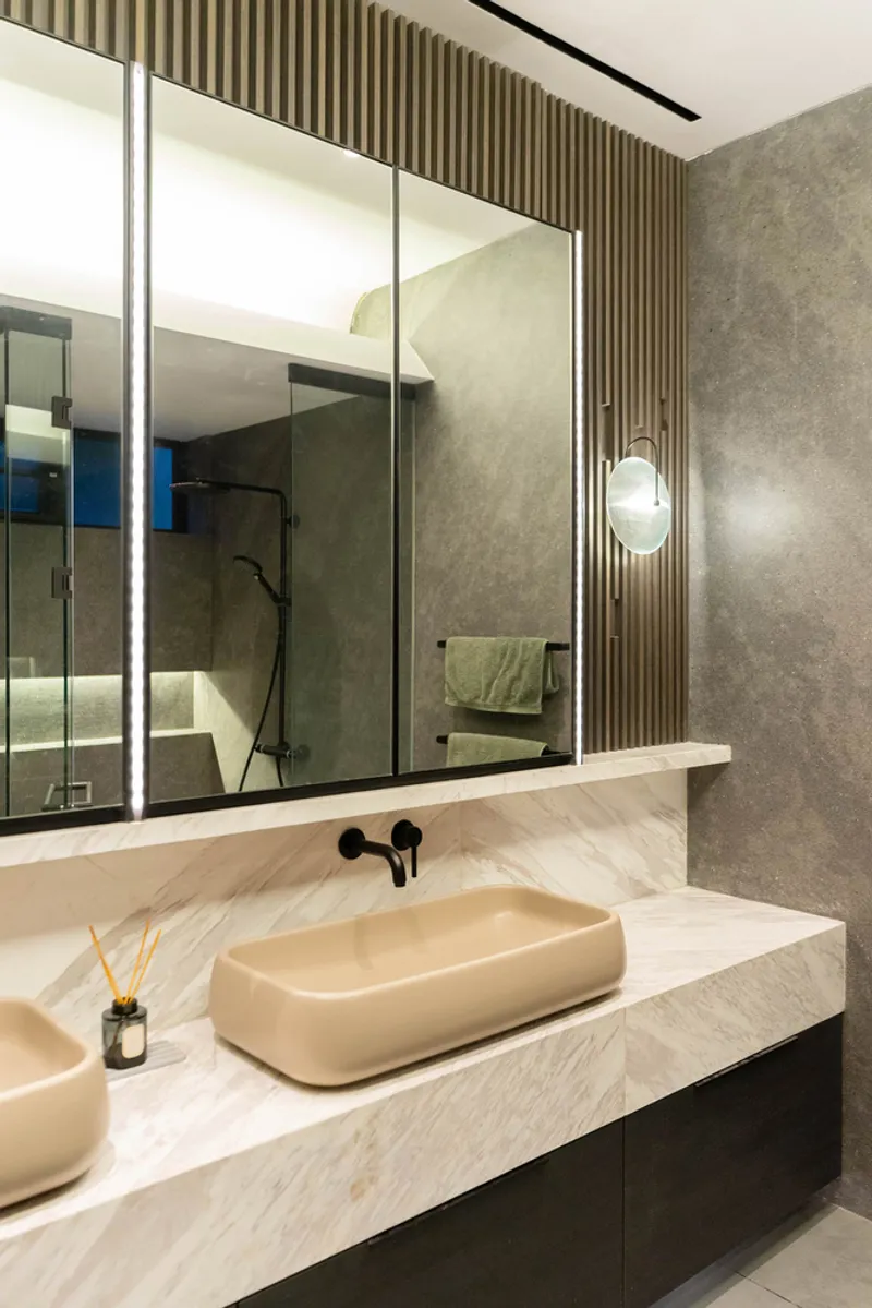 Double vanity with pale stone countertop, oval vessel sinks and vertical timber slat wall