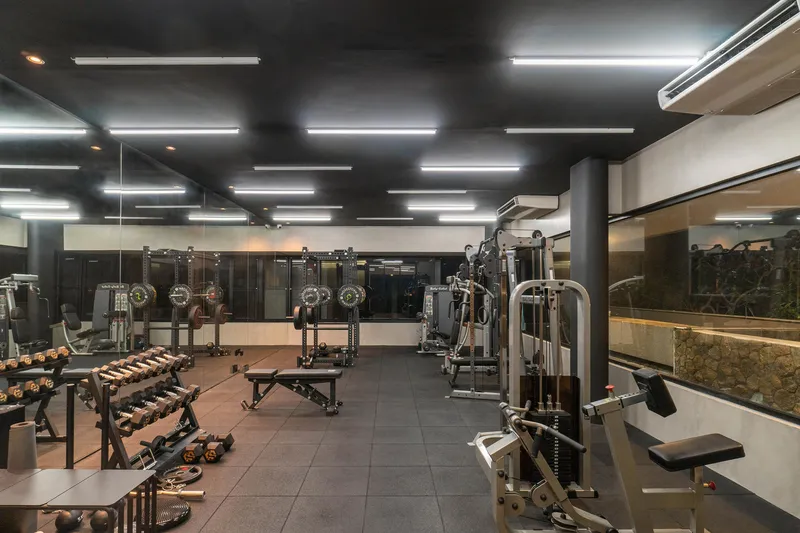 Gym interior with black ceiling grid, linear lighting and mirrored walls reflecting equipment