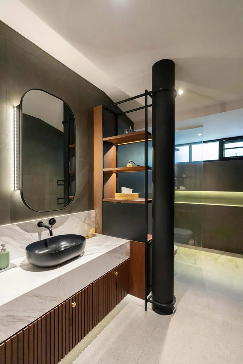 Bathroom vanity with black vessel sink, backlit oval mirror and open timber shelving beside cylindrical column